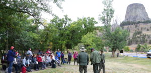 A group of people listening to three rangers in the mountains