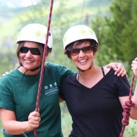 two women standing in the forest with rock climbing ropes