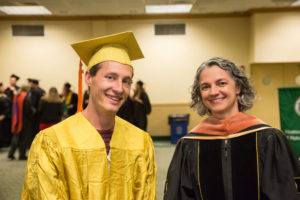 Man and woman in graduation robes smiling