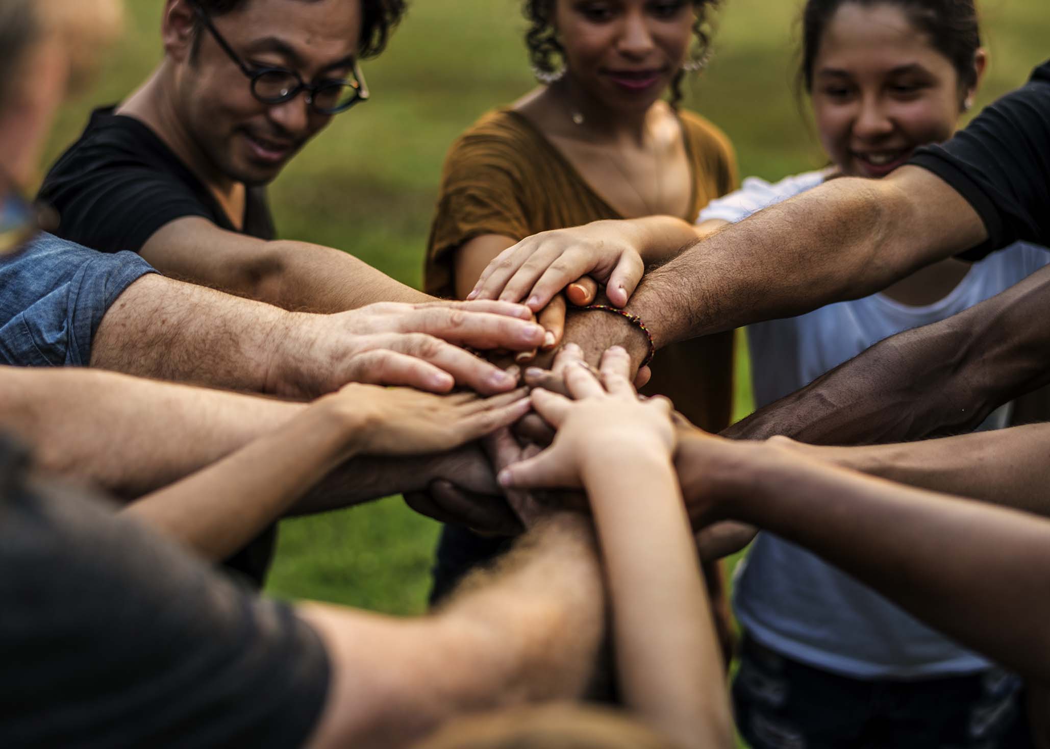 Group of diverse persons with their hands united in the center of the group