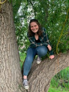 Esme crouches in a tree and smiles