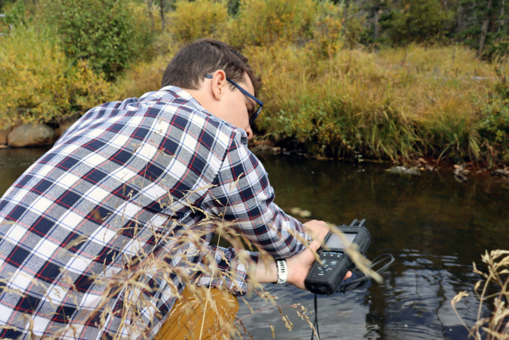 Professor Matt Ross measures water quality at the Poudre River in Colorado