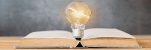 A shining lightbulb sits in the middle of an open book.